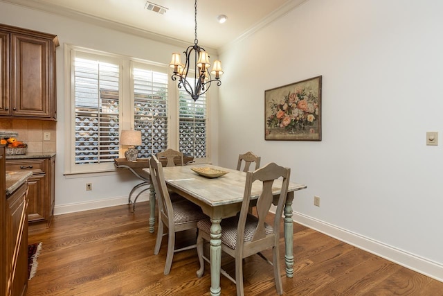 dining room with dark hardwood / wood-style floors, ornamental molding, and a notable chandelier