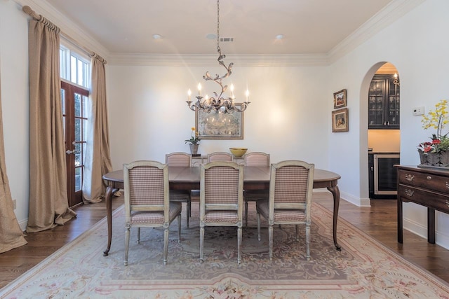 dining room with ornamental molding, dark hardwood / wood-style flooring, beverage cooler, and a notable chandelier