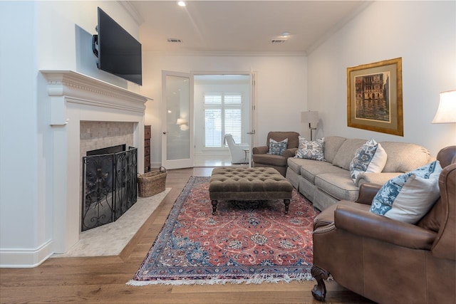 living room featuring a fireplace, hardwood / wood-style flooring, and crown molding