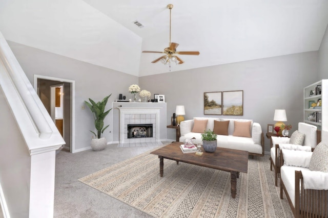 carpeted living room with ceiling fan, lofted ceiling, and a tiled fireplace