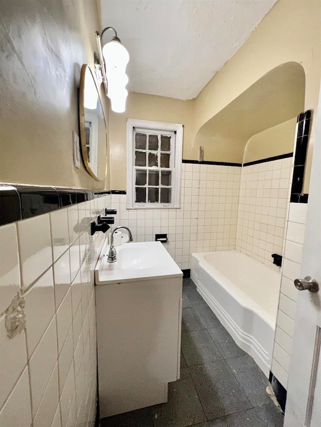 bathroom featuring a tub to relax in, vanity, and tile walls