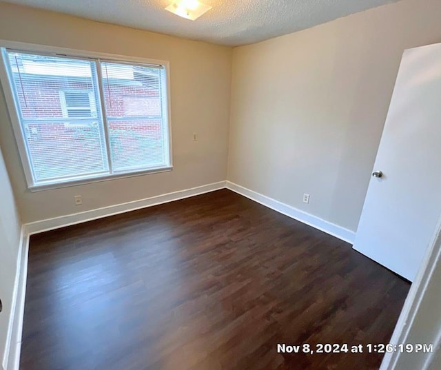 unfurnished room with a textured ceiling and dark hardwood / wood-style floors