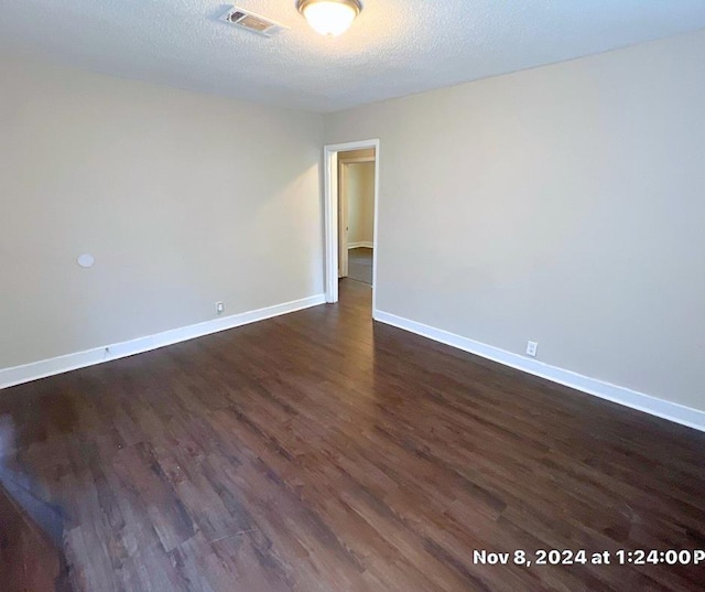 spare room featuring a textured ceiling and dark wood-type flooring