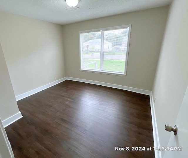 spare room with dark hardwood / wood-style flooring and a textured ceiling