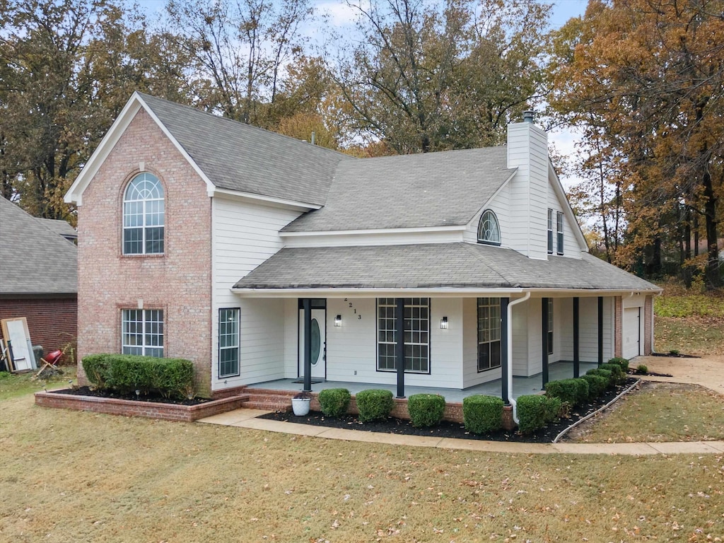 view of front of property featuring a front lawn, a porch, and a garage