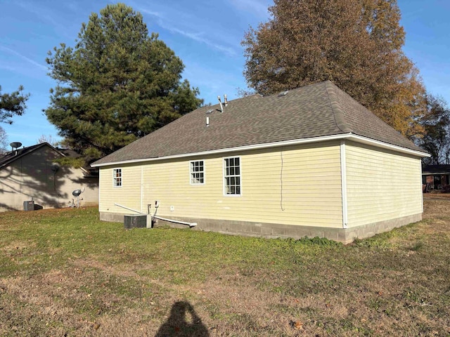 view of side of home with central AC unit and a lawn