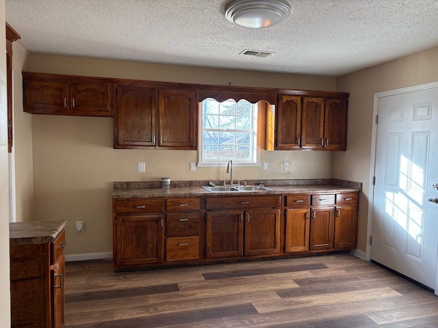 kitchen with a textured ceiling, dark hardwood / wood-style flooring, and sink