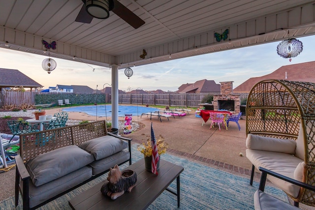 patio terrace at dusk with an outdoor living space with a fireplace and ceiling fan