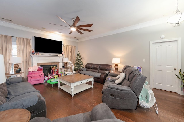 living room featuring ceiling fan, crown molding, dark wood-type flooring, and a tiled fireplace