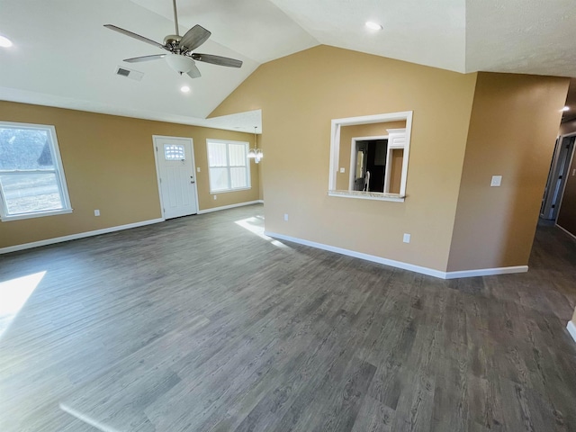 unfurnished living room featuring ceiling fan with notable chandelier, dark hardwood / wood-style flooring, and vaulted ceiling