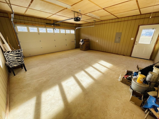 garage with wooden walls, electric panel, and a garage door opener