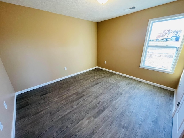 unfurnished room with a textured ceiling and dark hardwood / wood-style floors