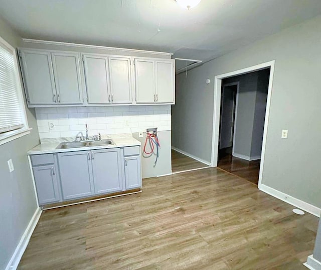 kitchen with tasteful backsplash, sink, and light hardwood / wood-style flooring