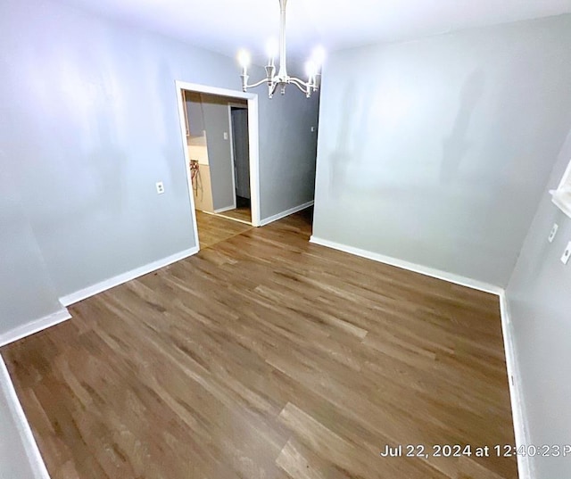 unfurnished dining area with hardwood / wood-style floors and an inviting chandelier