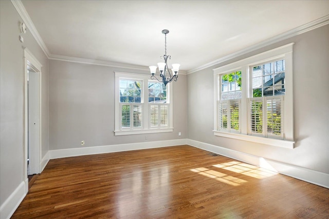 spare room with ornamental molding, plenty of natural light, a chandelier, and hardwood / wood-style flooring