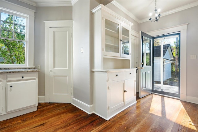 doorway featuring a chandelier, ornamental molding, and dark wood-type flooring