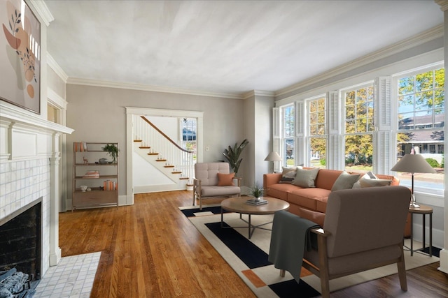 living area featuring crown molding, baseboards, stairway, a fireplace, and wood finished floors