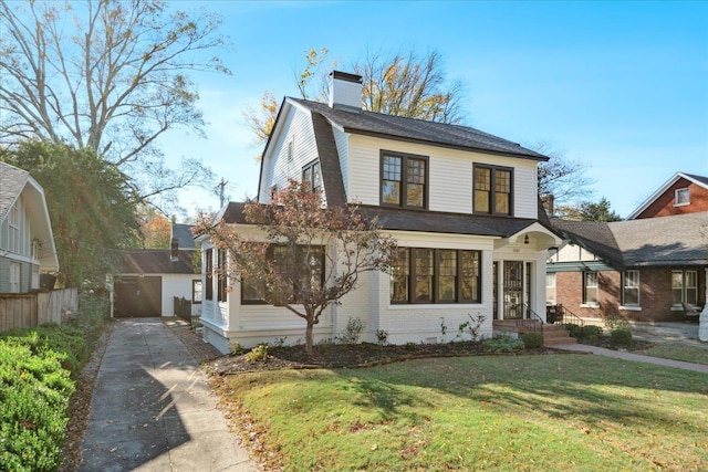 view of front of property featuring a garage, an outbuilding, and a front lawn