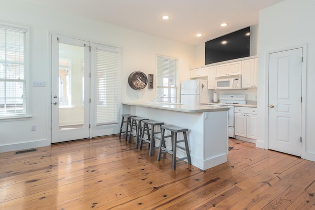 kitchen with kitchen peninsula, white cabinetry, white appliances, and light wood-type flooring