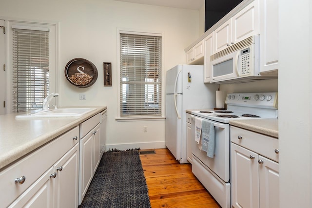 kitchen with a wealth of natural light, sink, light hardwood / wood-style flooring, white appliances, and white cabinets