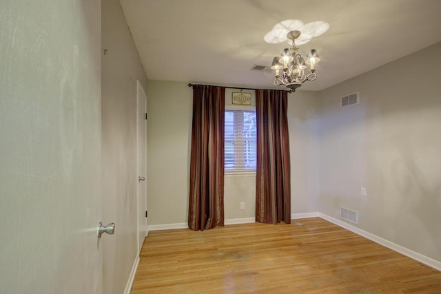 unfurnished room featuring light hardwood / wood-style floors and an inviting chandelier