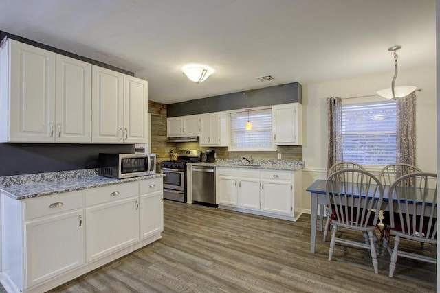 kitchen featuring sink, light hardwood / wood-style flooring, light stone counters, white cabinetry, and stainless steel appliances