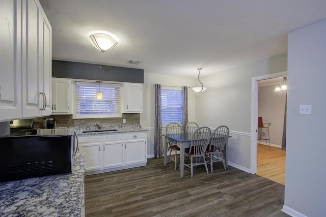 kitchen with white cabinets, hanging light fixtures, dark wood-type flooring, and sink