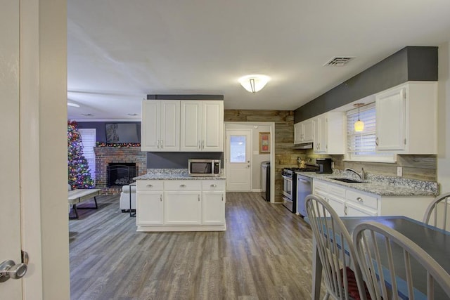 kitchen featuring sink, decorative light fixtures, light hardwood / wood-style floors, white cabinetry, and stainless steel appliances