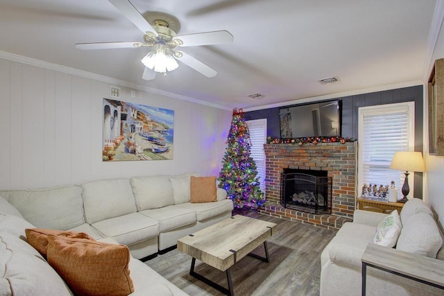 living room featuring hardwood / wood-style floors, a fireplace, ceiling fan, and crown molding