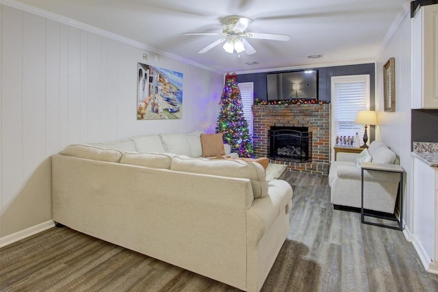 living room with ceiling fan, wood-type flooring, ornamental molding, and a brick fireplace