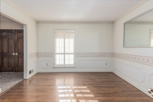 spare room featuring dark wood-style floors, wainscoting, visible vents, and crown molding