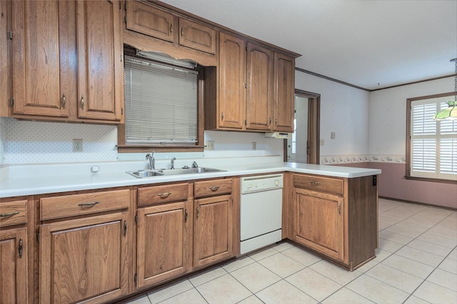 kitchen featuring dishwasher, wainscoting, a peninsula, light countertops, and a sink