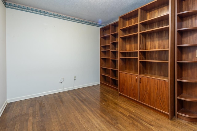 spare room with dark wood-style flooring, a textured ceiling, and baseboards