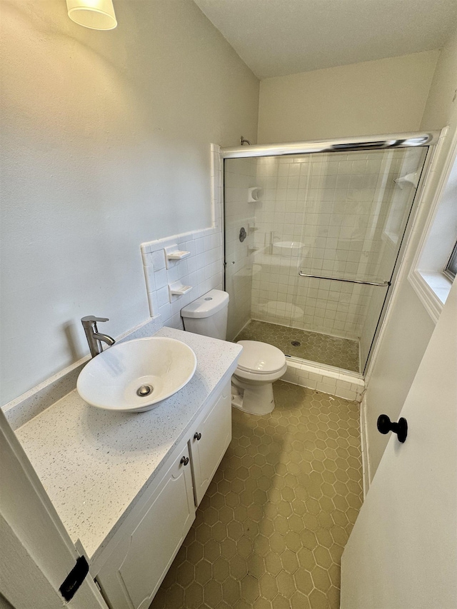 bathroom with tile patterned floors, vanity, toilet, and walk in shower