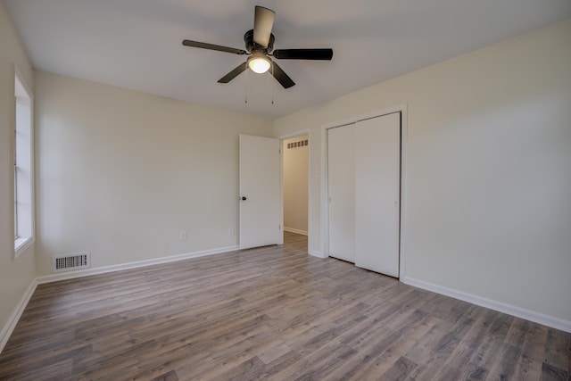 unfurnished bedroom featuring hardwood / wood-style floors, ceiling fan, and a closet