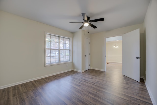 unfurnished room with dark hardwood / wood-style flooring and ceiling fan with notable chandelier