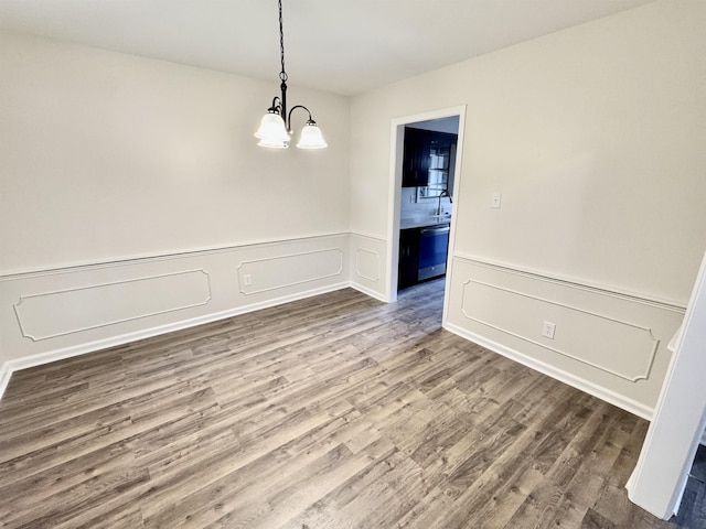 unfurnished dining area with wood-type flooring and a notable chandelier