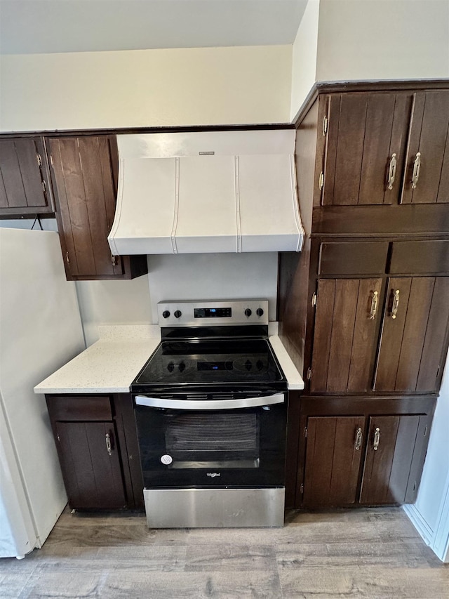 kitchen featuring electric range, white refrigerator, light wood-type flooring, and ventilation hood