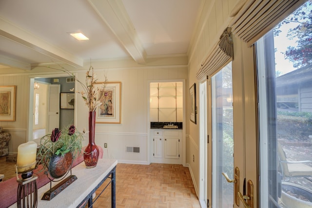 doorway to outside featuring beamed ceiling, sink, crown molding, and light parquet floors