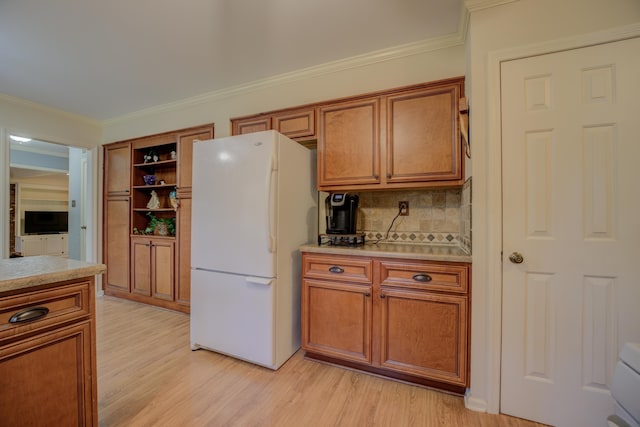 kitchen with light wood-type flooring, white fridge, and crown molding