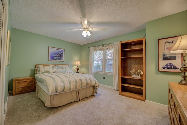 bedroom with ceiling fan, light colored carpet, and a textured ceiling