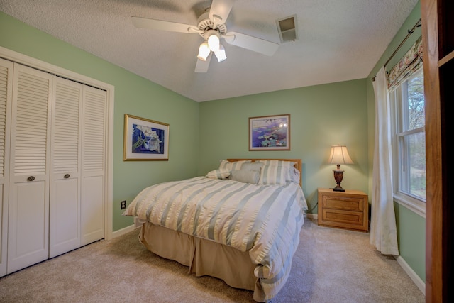 carpeted bedroom featuring ceiling fan, a textured ceiling, and a closet