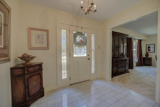 entrance foyer featuring an inviting chandelier, light colored carpet, and ornamental molding