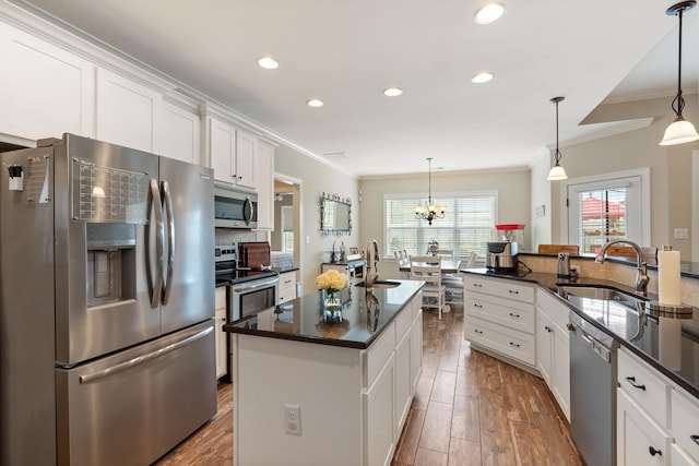 kitchen with a kitchen island with sink, white cabinets, hanging light fixtures, and appliances with stainless steel finishes