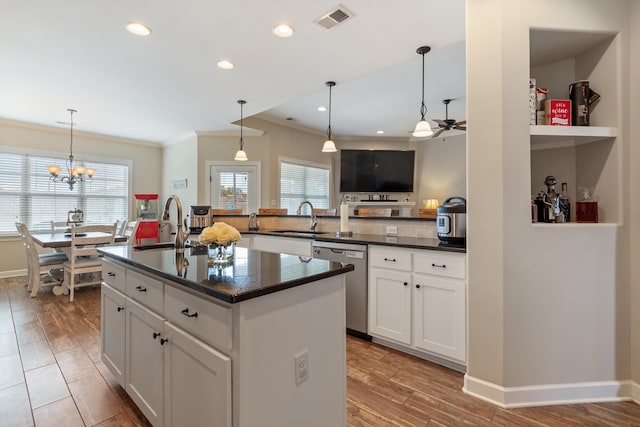 kitchen with white cabinetry, an island with sink, stainless steel dishwasher, and ceiling fan with notable chandelier