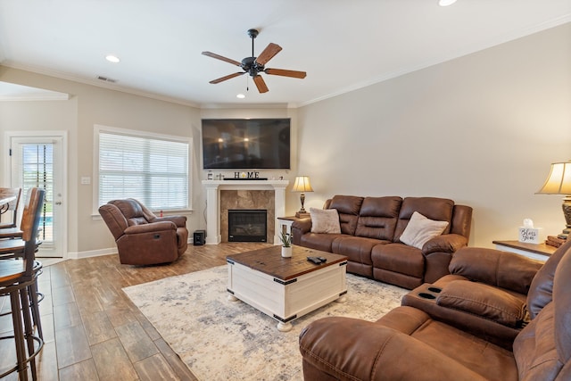 living room with crown molding, a fireplace, ceiling fan, and hardwood / wood-style flooring