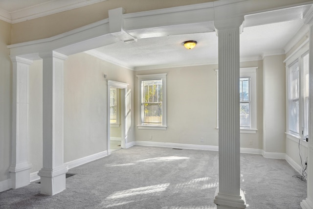 carpeted spare room featuring decorative columns, crown molding, and a healthy amount of sunlight