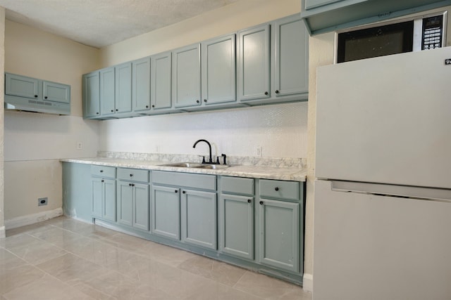 kitchen featuring sink, white fridge, a textured ceiling, and light tile patterned floors