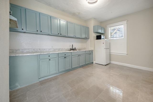 laundry room with light tile patterned flooring, a textured ceiling, and sink