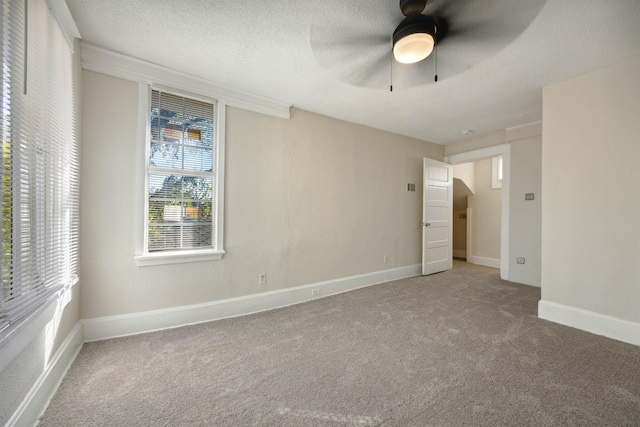 unfurnished room with carpet flooring, ceiling fan, and a textured ceiling